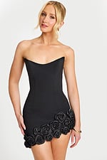Model wearing fitted black dress with sculpted floral appliqué