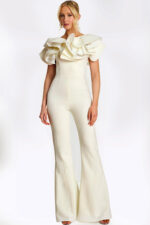 Elegant white jumpsuit with dramatic ruffled shoulders and pearl safety pin accents