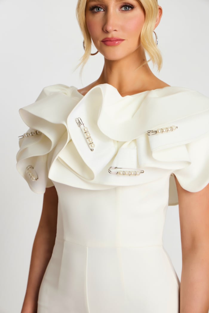 Front close-up of white jumpsuit highlighting textured ruffles and embellishments