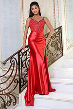 red beaded corset satin prom dress with high slit - front full body, smiling on stairs hand on banister