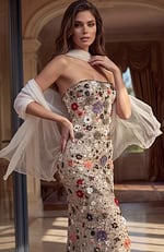 A luxurious strapless column dress in a champagne hue with dense floral embroidery and a matching sheer wrap.