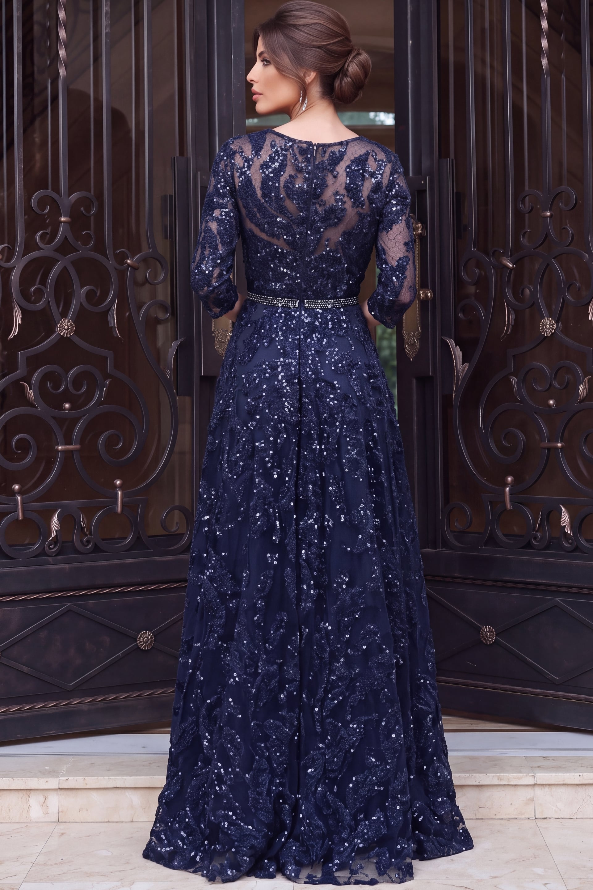 Navy sequin lace gown photographed from behind showing sleeve detail and floor length hem