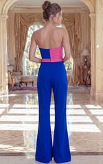 Elegant wide-leg jumpsuit in cobalt blue with a contrasting fuchsia pink asymmetrical neckline and cinched waist.