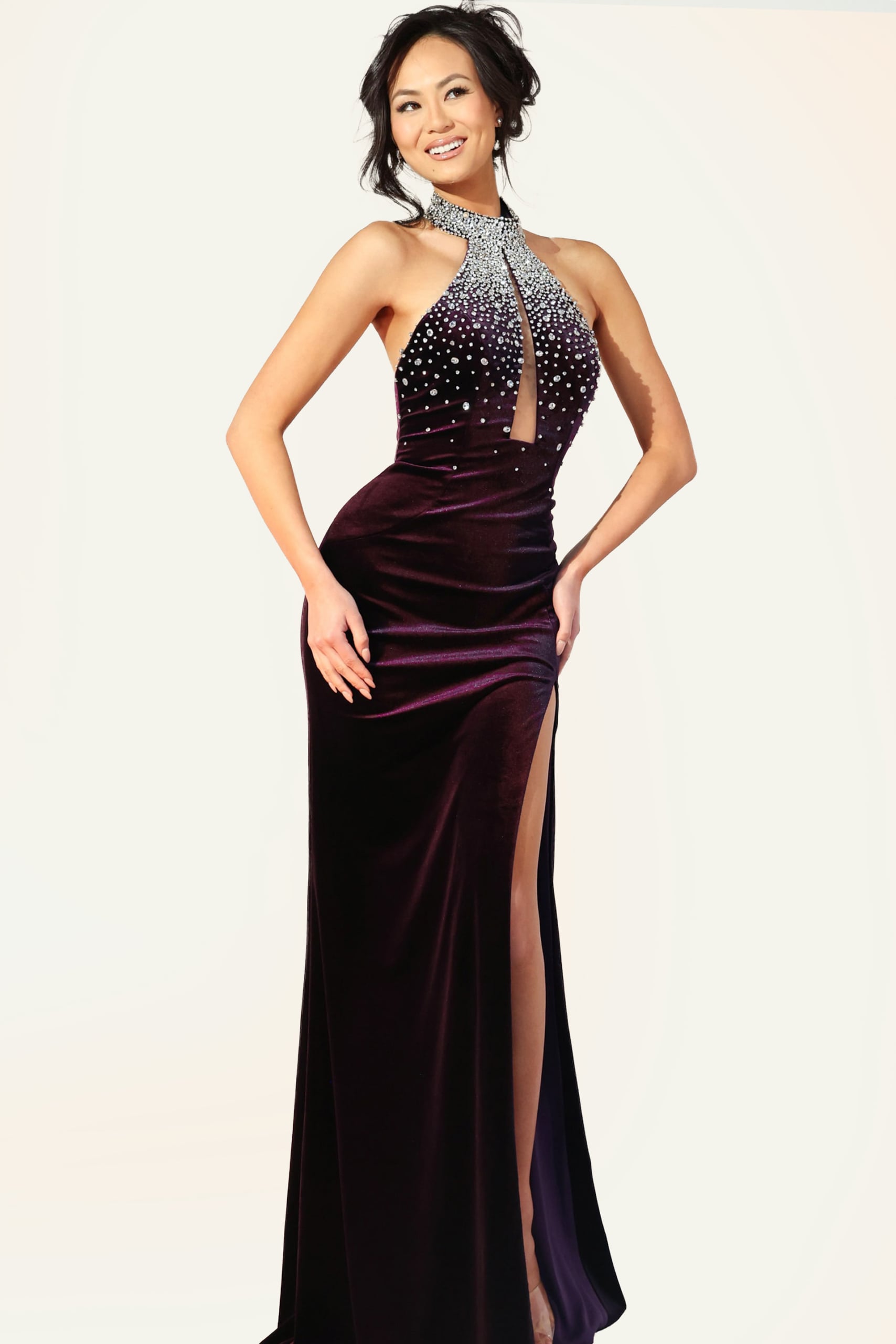 Deep plum velvet halter gown with crystal embellished neckline, open back, keyhole cutout, and high side slit
