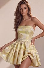 A vibrant yellow strapless dress featuring a shimmering floral brocade pattern and a short, two-tier ruffled skirt.