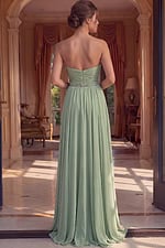 Back view of a strapless coral gown showing a ruched back design with a centered zipper and a full chiffon train.
