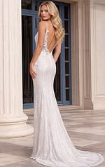 Back view of a form-fitting white sequin gown showcasing a dramatic low-cut open back and a mermaid-style skirt with a short train.