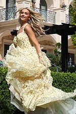 champagne halter polka dot tiered dress with bow bodice - three quarter view, smiling wind-swept hair twirling skirt