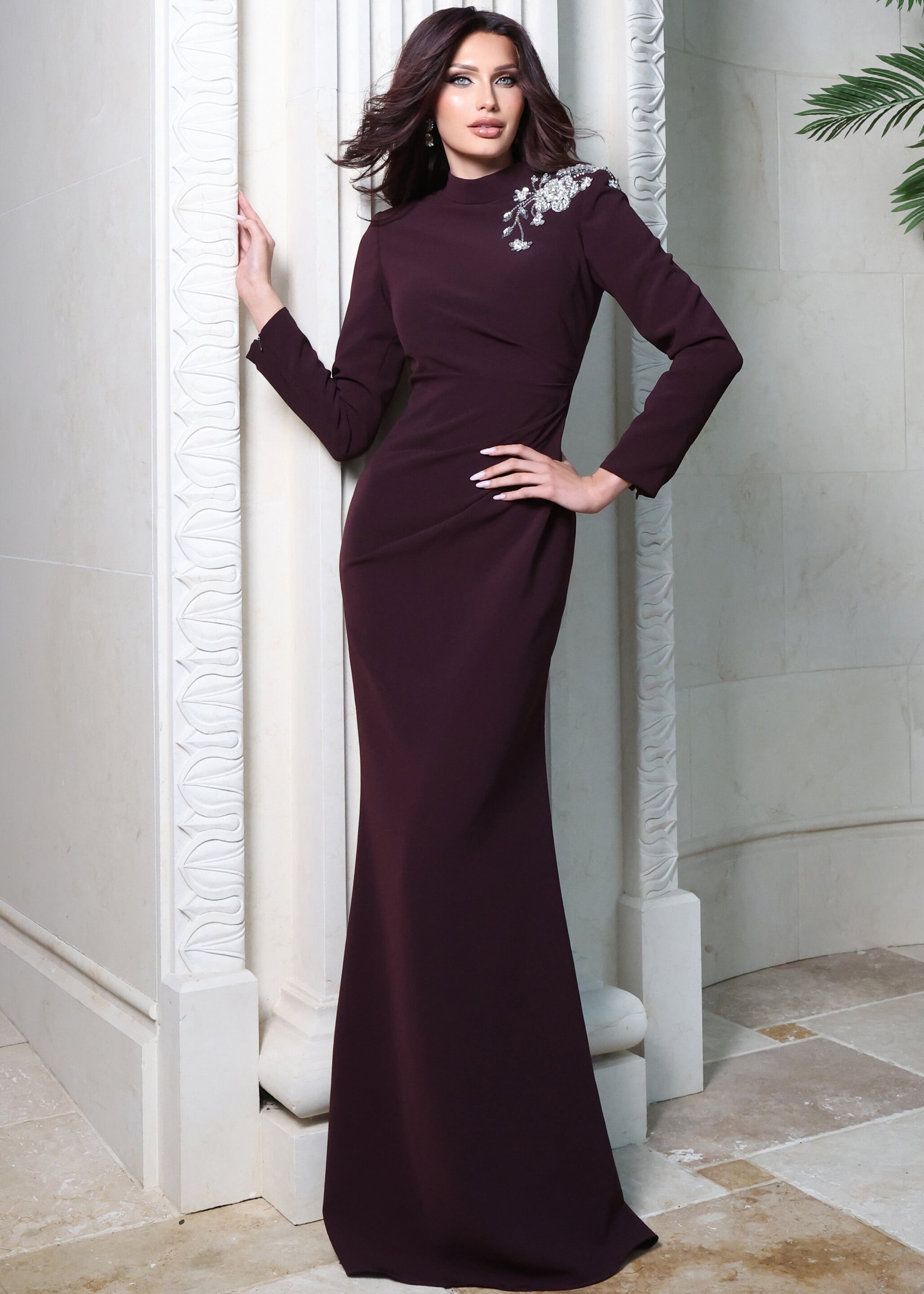 Deep plum long-sleeve gown with high neckline and floral appliqué at shoulder, front view