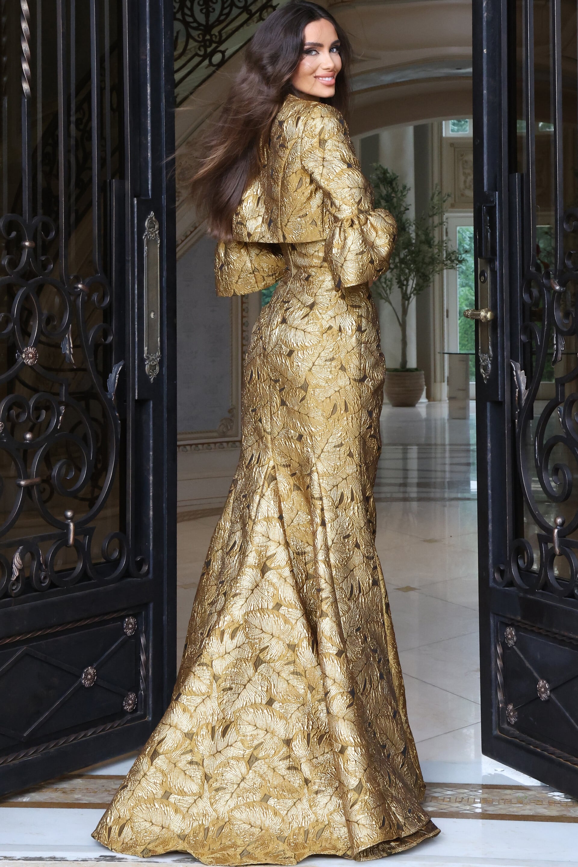 Gold metallic textured mermaid gown with bell-sleeve jacket bodice, back view
