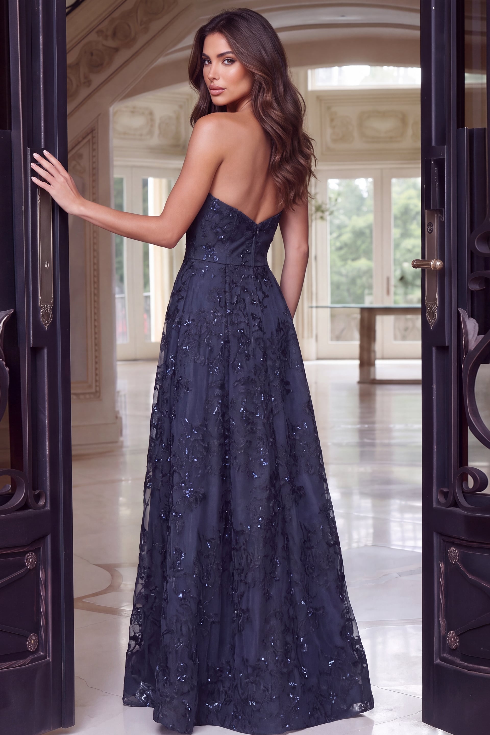 Photographed from behind, the midnight lace gown drops from a sweetheart back into a full sweep