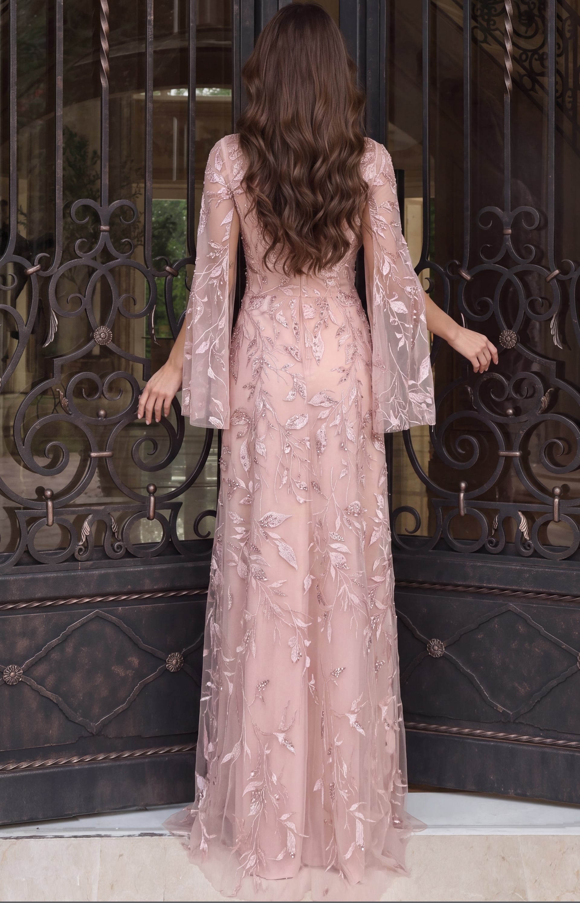 Standing with her back to the camera in a pink sequinned leaf-embroidered tulle gown