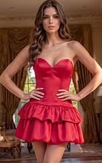 Vibrant red party dress with a form-fitting corset-style bodice and a sculptural, high-volume ruffled bottom.