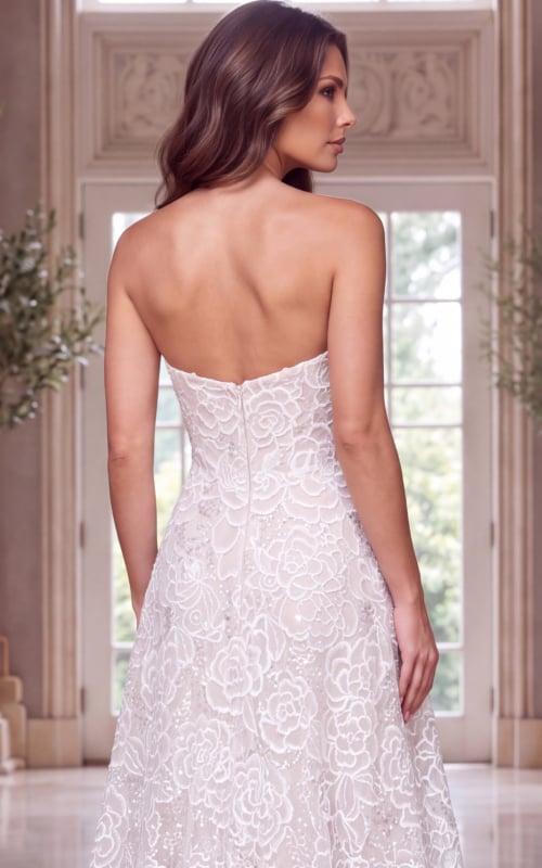 Rear crop framing the bare shoulders, back zip and floral lace skirt of a strapless gown