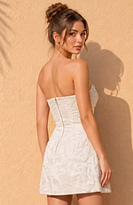 Sophisticated bridal-white mini dress blending a minimalist strapless cut with maximalist, textured floral appliqués.