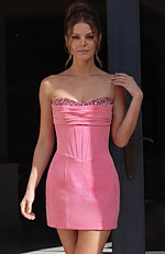 Form-fitting pink cocktail dress featuring vertical boning details on the torso and a layered fabric wrap across the bust.