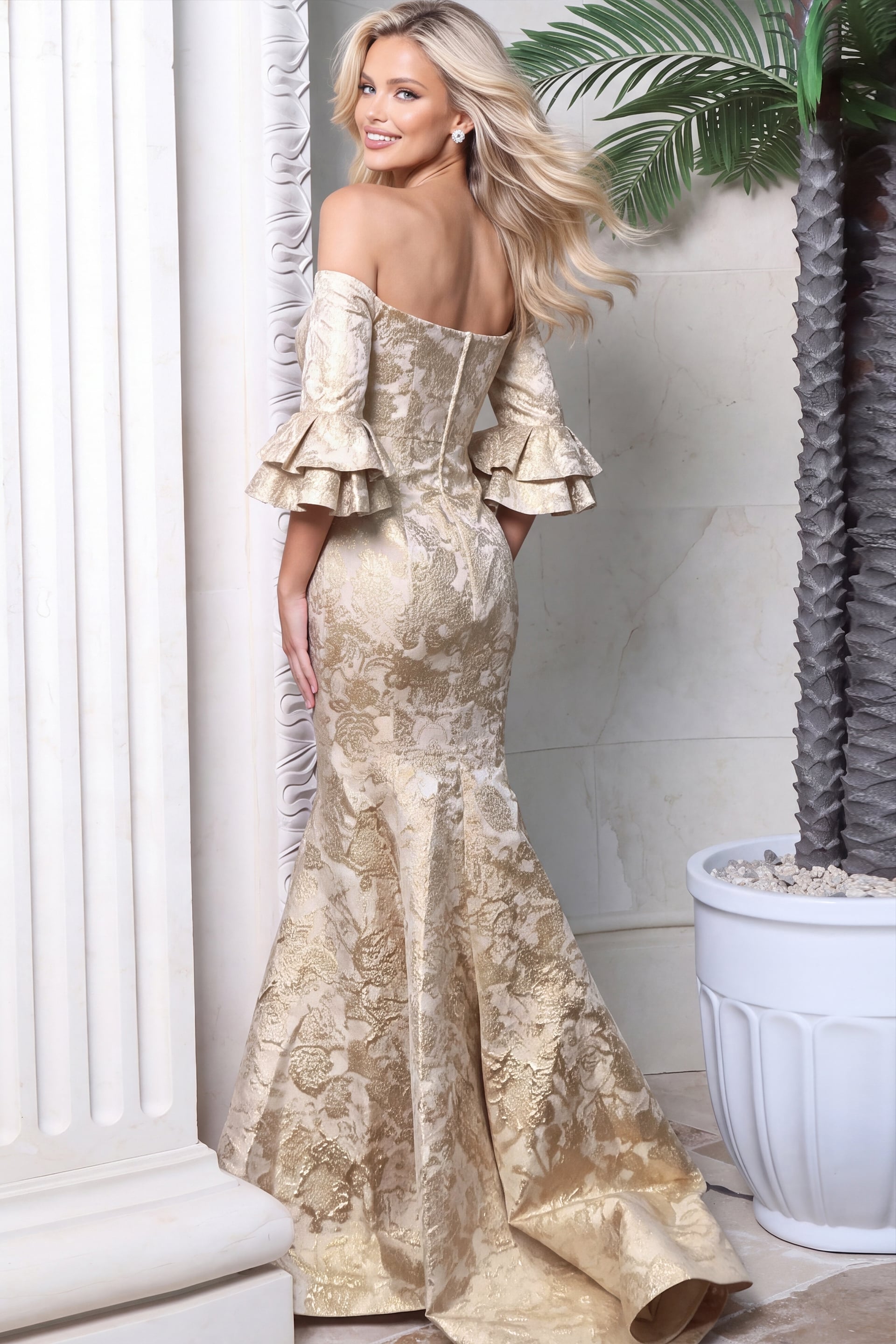 Back view of ivory and gold jacquard mermaid gown with off-shoulder sleeves and train