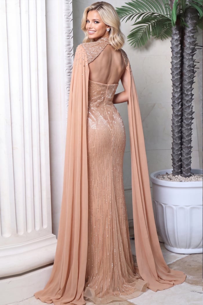 Open-back nude beaded mermaid gown seen from behind with sweeping chiffon cape panels