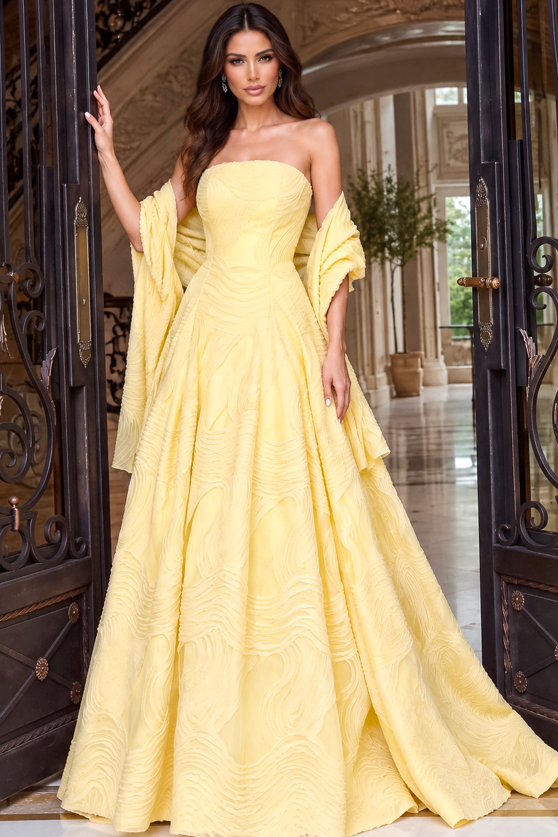 Strapless pastel yellow ball gown with a sculpted bodice and wide skirt held by a stole