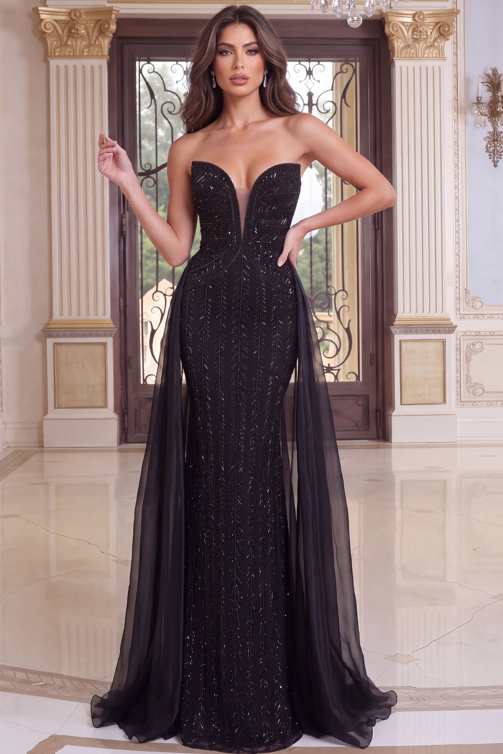 Head-to-toe view of a beaded black mermaid gown with plunging bodice and chiffon streamers