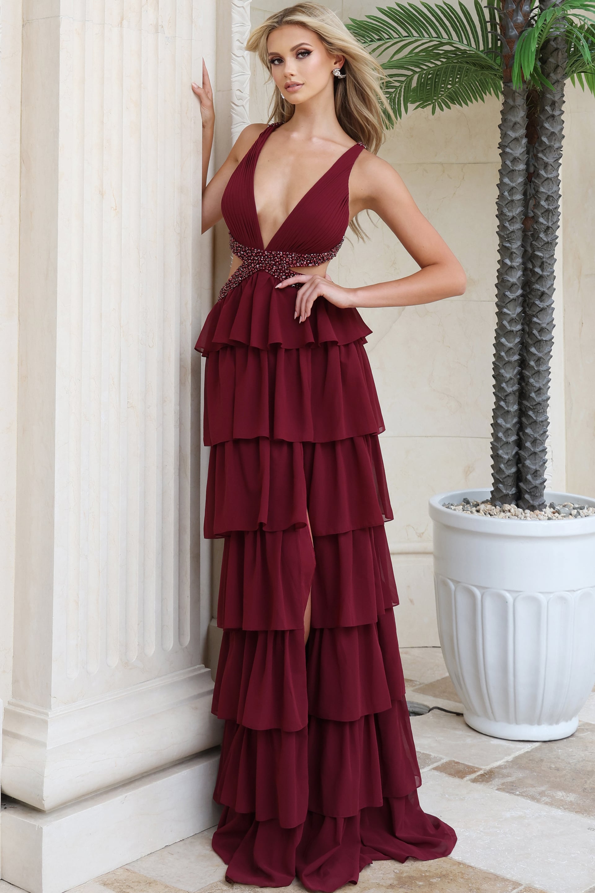 Burgundy plunging V neck gown with hand on hip showing beaded waist detail