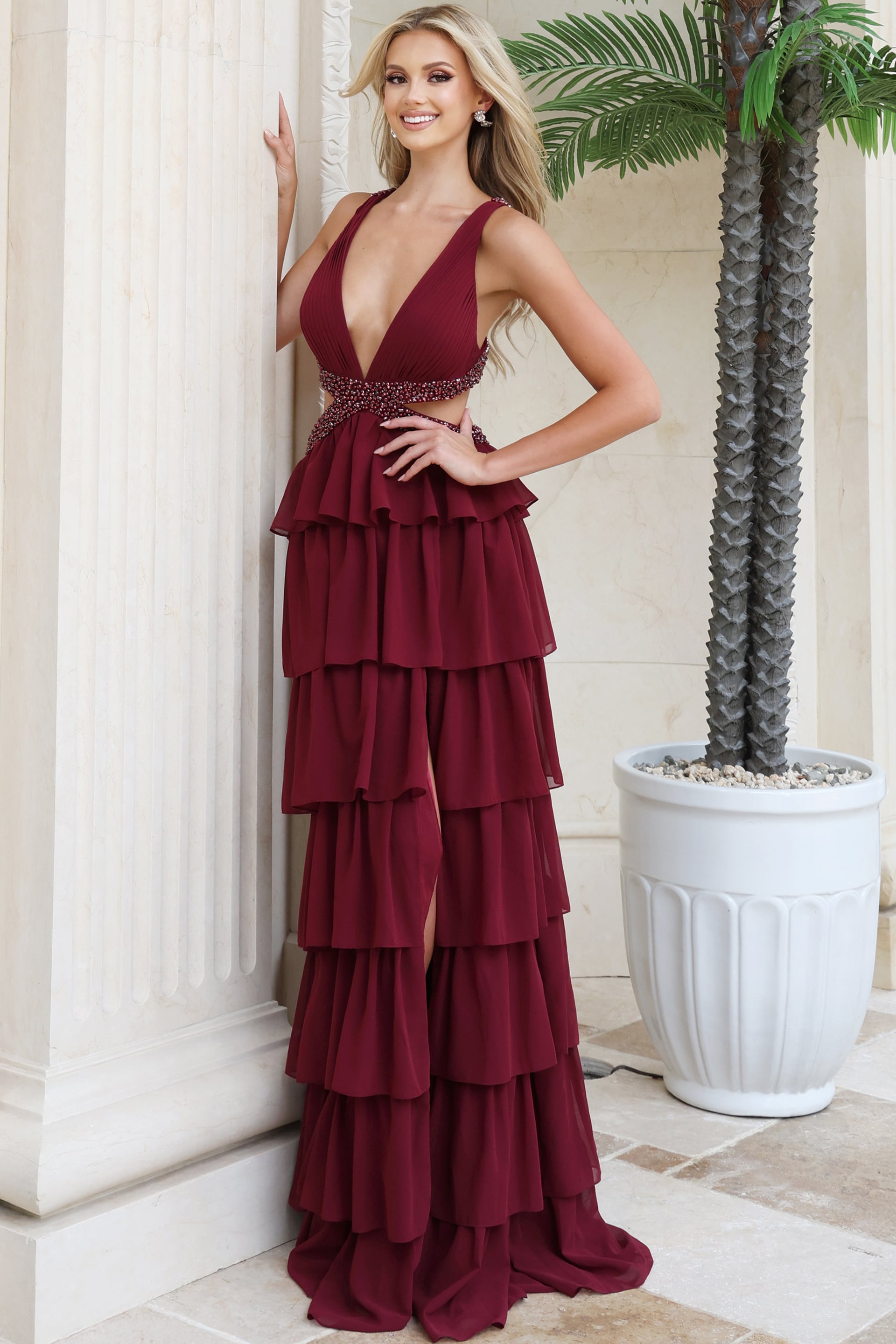 Burgundy plunging V neck chiffon gown shown from the front with arm raised