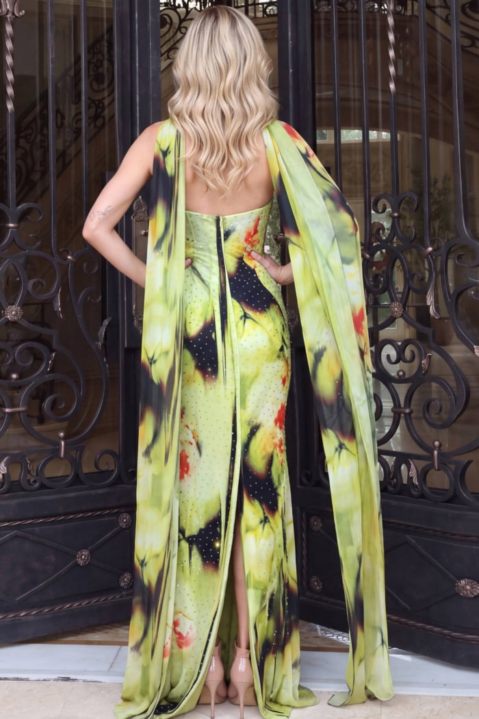Long chiffon side panels frame the bare open back of a chartreuse floral gown, rear view