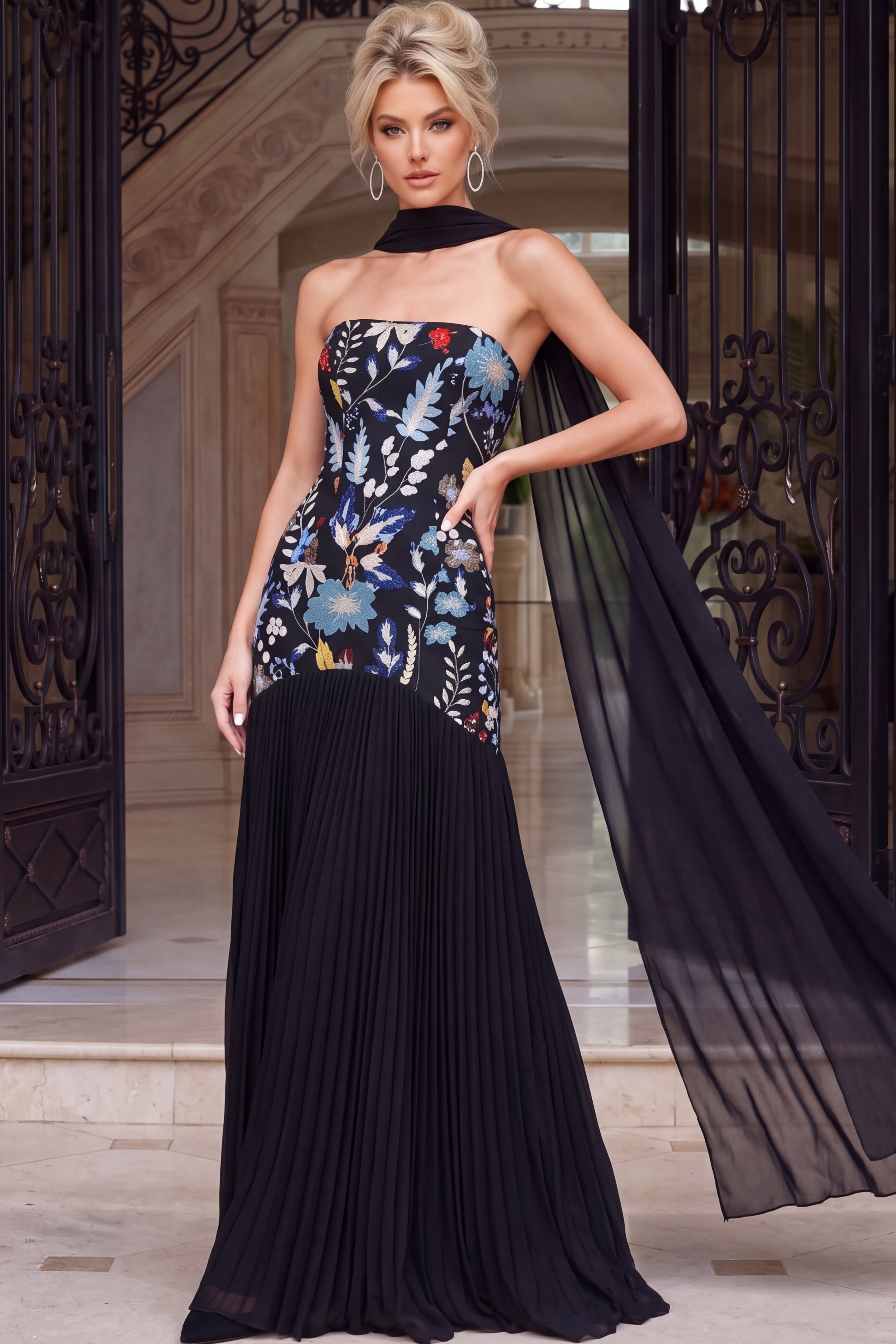 Strapless black gown with multicolor floral embroidery and pleated skirt.