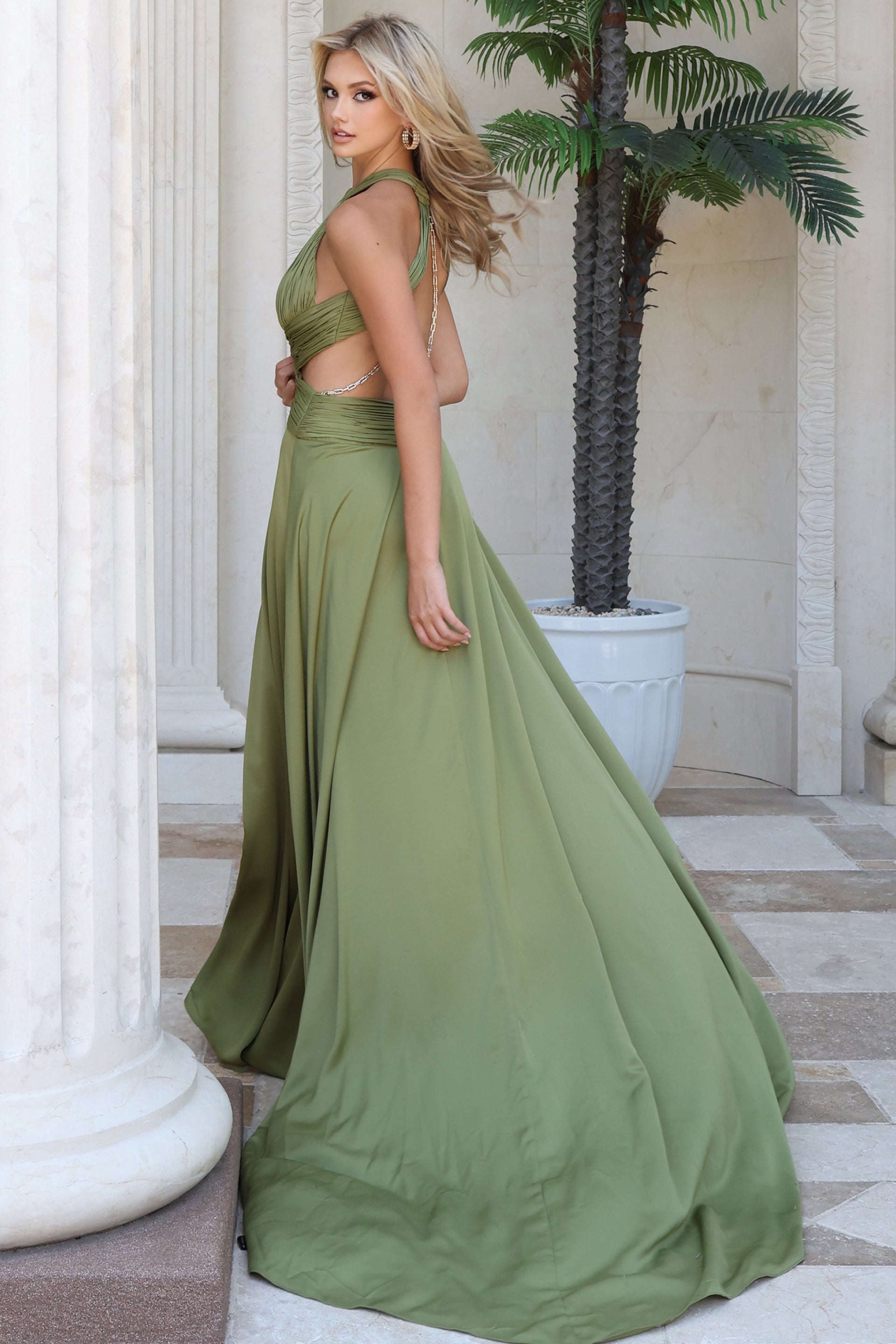 Olive satin halter gown shown from the side with flowing skirt and sweep train