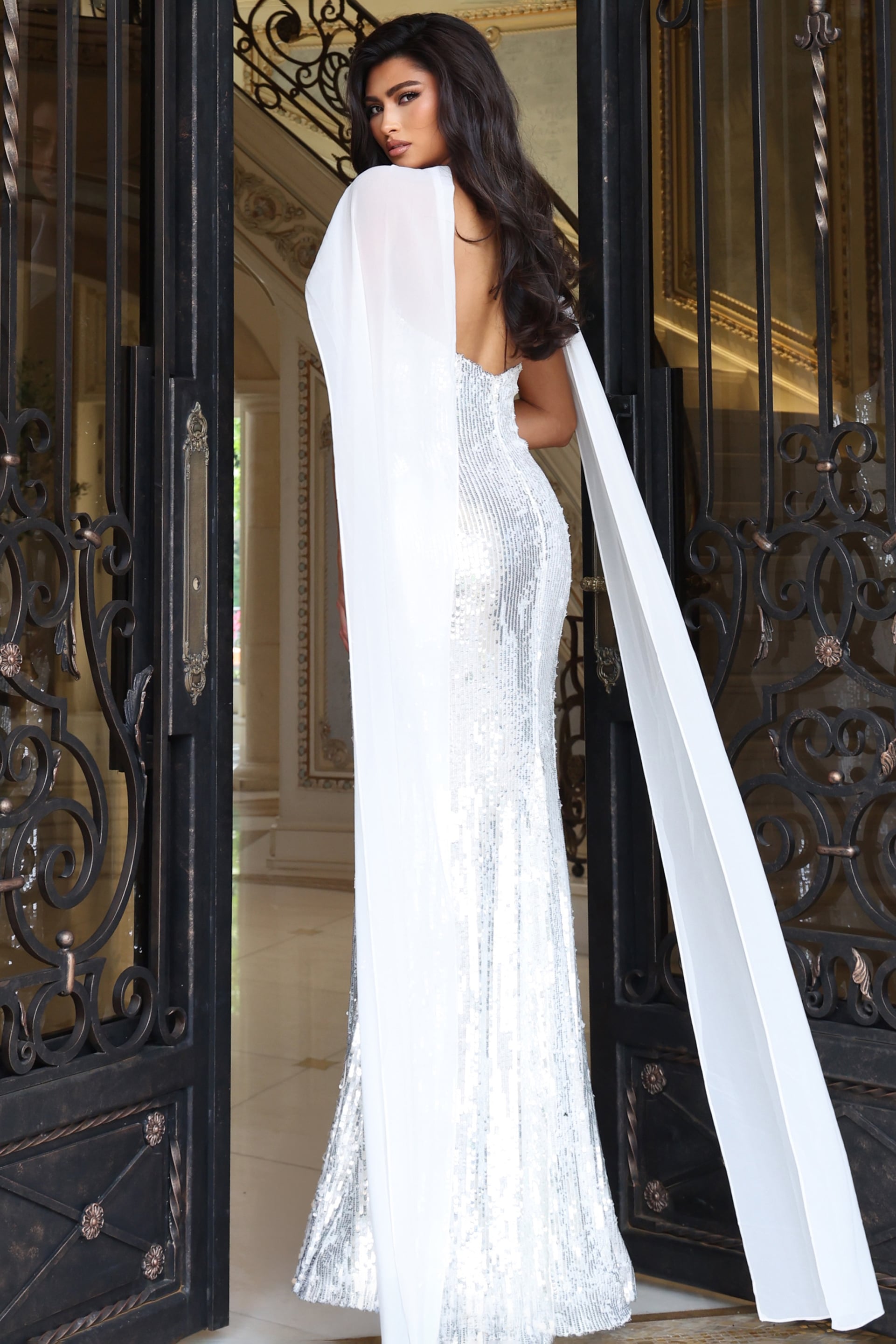 Back view of ivory sequin gown showing low open back and floor length cape