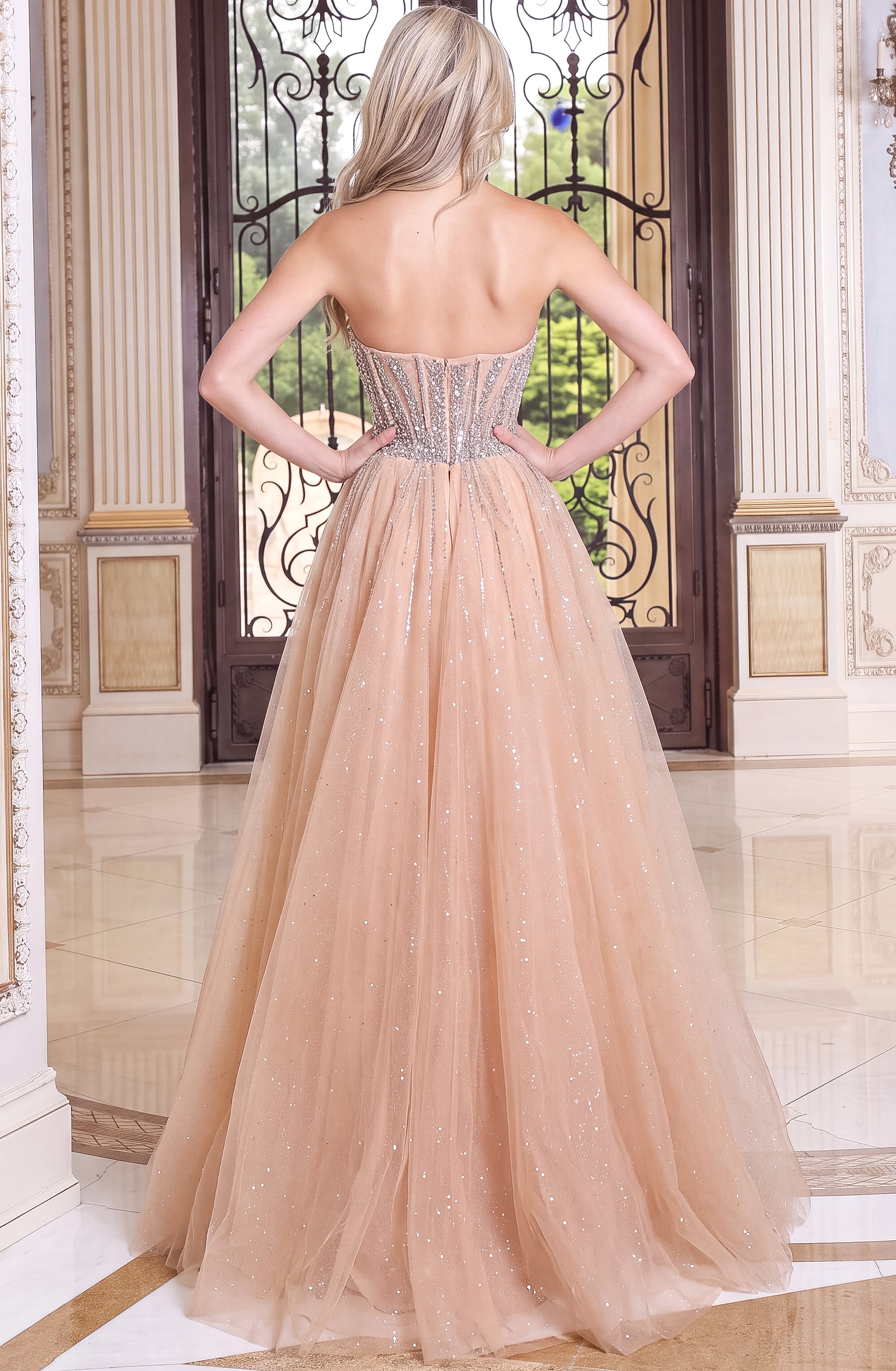 back view of nude beaded sweetheart sheath gown with high slit and tulle overskirt