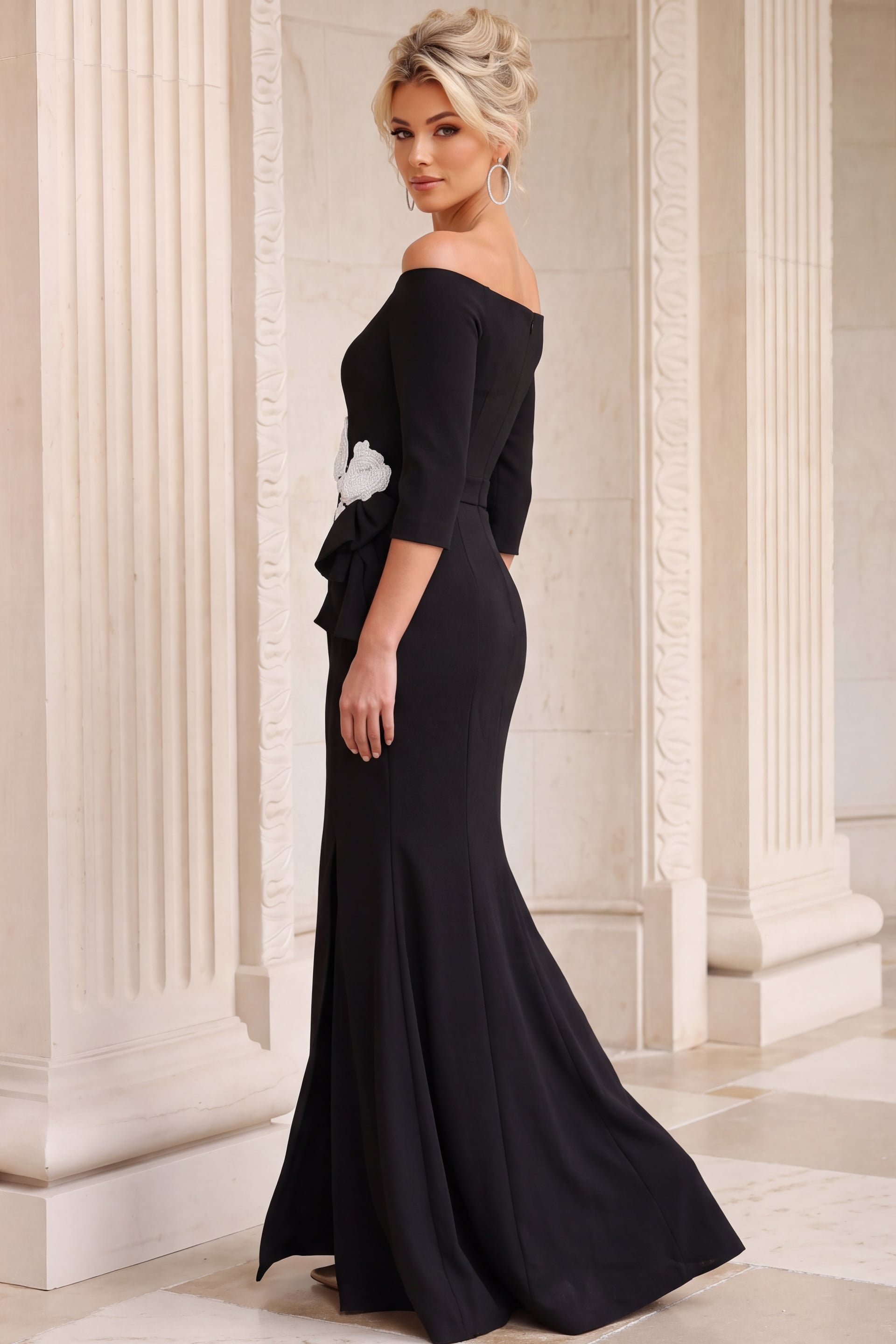 Side profile of a sleeved black crepe gown with hip drape and long fluted skirt