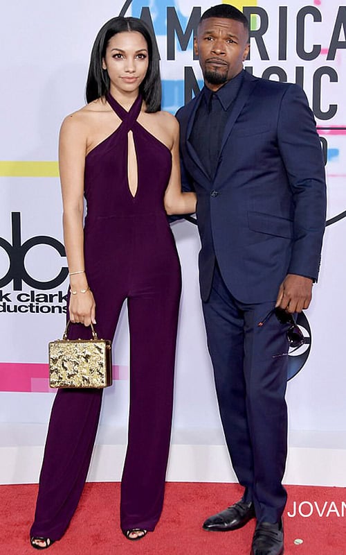 Model wearing Jovani 50908 dress with a halter neckline and keyhole cutout, full-length in purple, standing next to a companion.