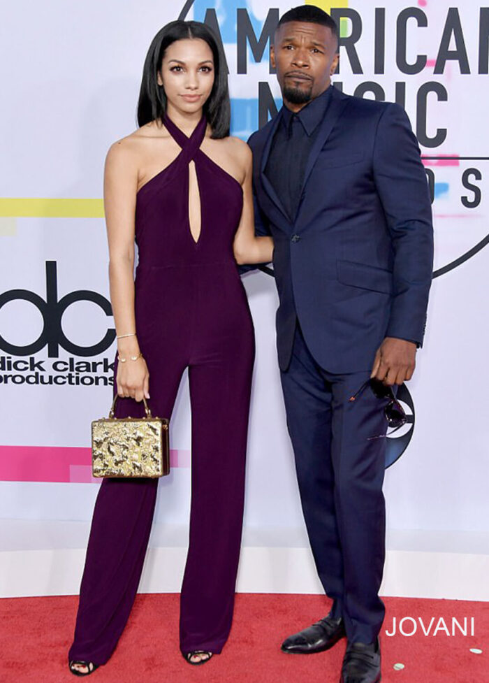 Model wearing Jovani 50908 dress with a halter neckline and keyhole cutout, full-length in purple, standing next to a companion.