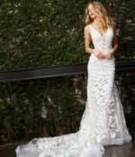 Model wearing Jovani JB04192 white gown with V-neckline standing outdoors