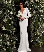 Model presenting Jovani JB06911 ivory gown with plunging neckline in a floral setting.