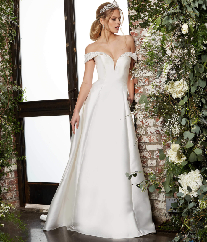 Model in Jovani JB07134 ivory dress with a romantic off-the-shoulder style and beaded details, front view.