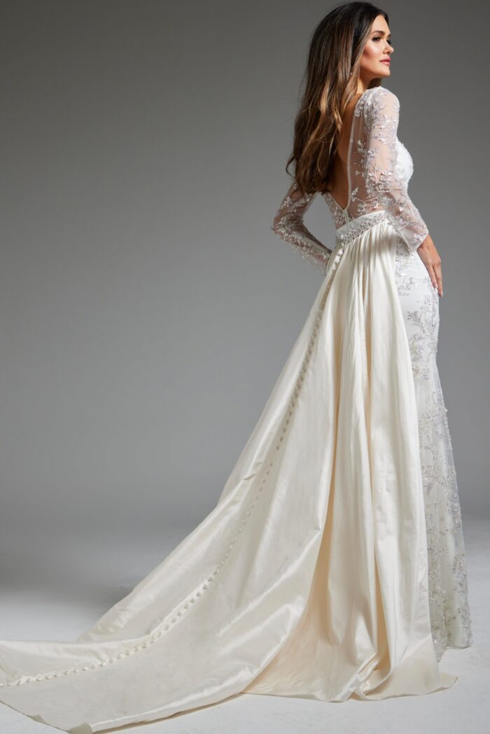 Back view of model wearing Jovani JB07376 white gown with low-cut back and flowing overskirt.