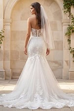 Back view of a strapless lace mermaid gown with sheer back, button closure, and long tulle train.