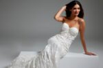 Model in Jovani JB07583 white gown sitting, showing detailed lace pattern and fit.