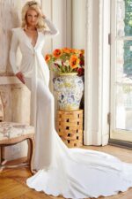 Model wearing Jovani JB23181 elegant white gown with V-neckline and long sleeves