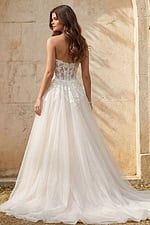 Back view of a strapless lace gown with sheer corset bodice and flowing tulle skirt.