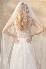 Back view of sheer floral lace wedding dress with buttons and long veil