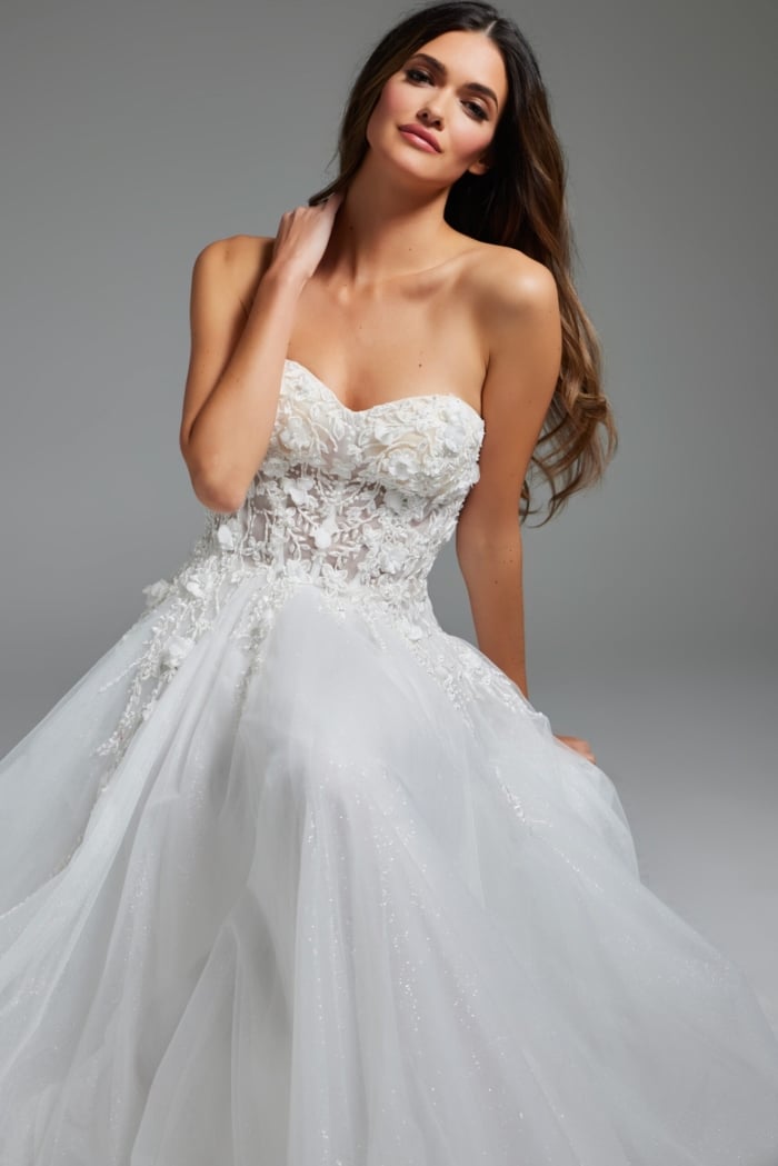 Model in Jovani JB39160 sitting gracefully, showcasing a white dress with floral applique bodice.