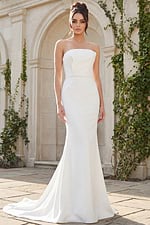 A sleek strapless fit and flare bridal gown featuring clean lines, soft structure, and a button-detailed back for a refined modern look.
