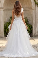 Back view of an A-line bridal gown with layered tulle skirt, illusion lace bodice, and 3D floral shoulder detail.