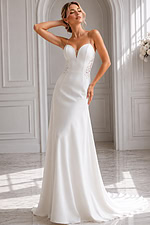 Timeless bridal silhouette with a clean, flowing skirt, illusion lace details, and a striking low V-back.