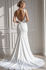 Contemporary wedding gown featuring a plunging V-neck bodice, soft floral appliqué at the shoulder, and a sleek crepe skirt that gently flares below the hips into a graceful,