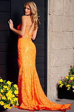 Model wearing Jovani 23216 orange dress with sequins, back view near flowers.