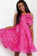model wearing K23682 fuchsia dress with floral embellishments, front view, holding skirt